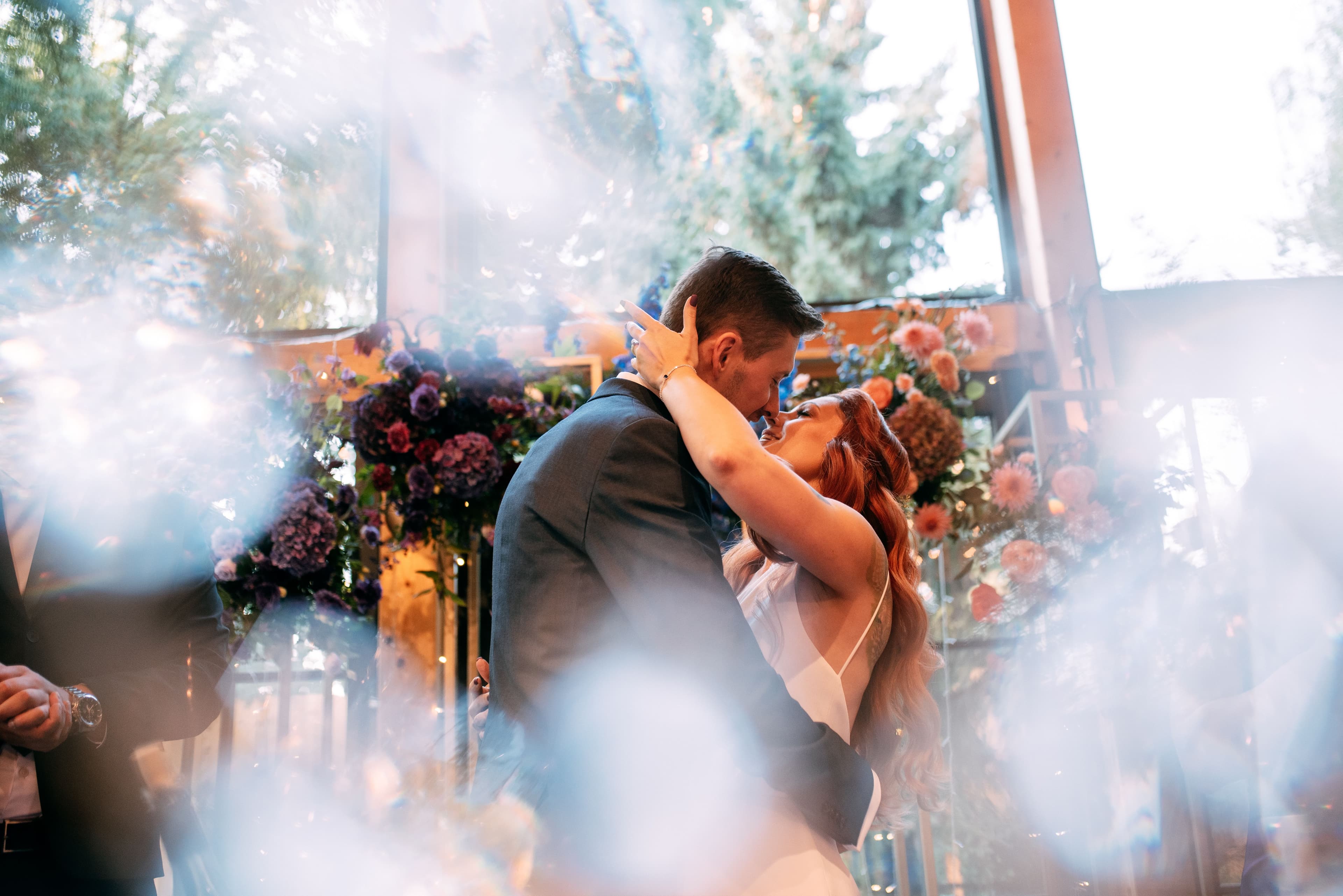 Para tańcząca przy łuku kwiatowym z różami i zielenią, światło słoneczne, bokeh w tle