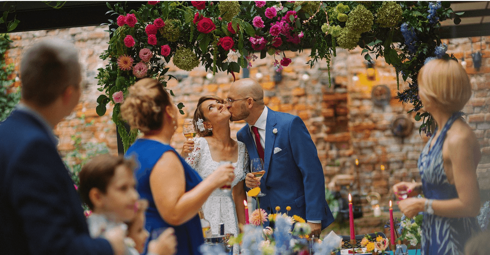 Ścianka za stołem prezydialnym z kwiatami w kolorze fuksji, zieleni i niebieskim