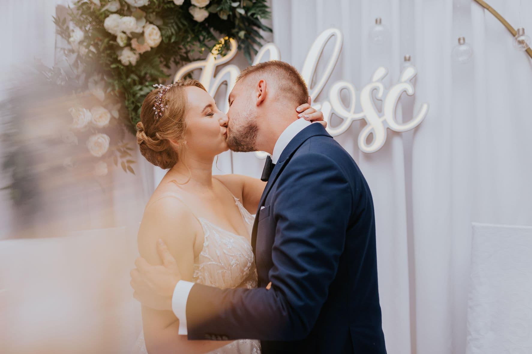 Kwiatowa obręcz z świetlistym napisem.