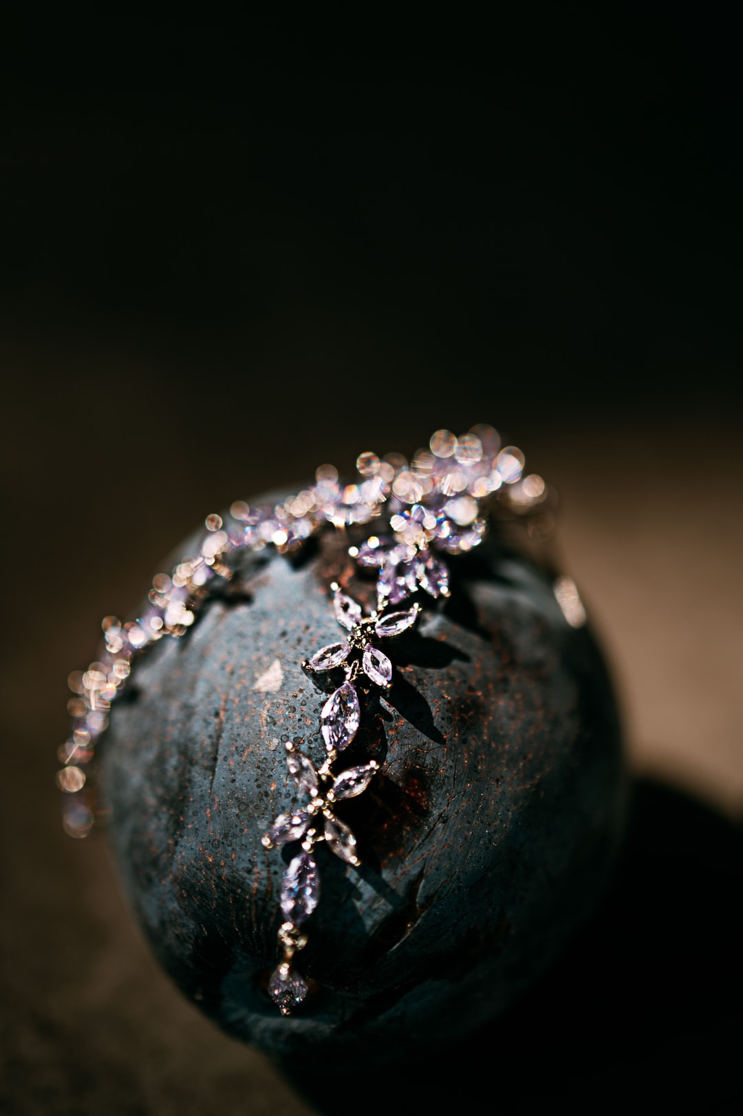 Srebrna biżuteria ślubna z kryształkami na ciemnym kamieniu, zbliżenie na delikatną kompozycję z kwiatowymi motywami