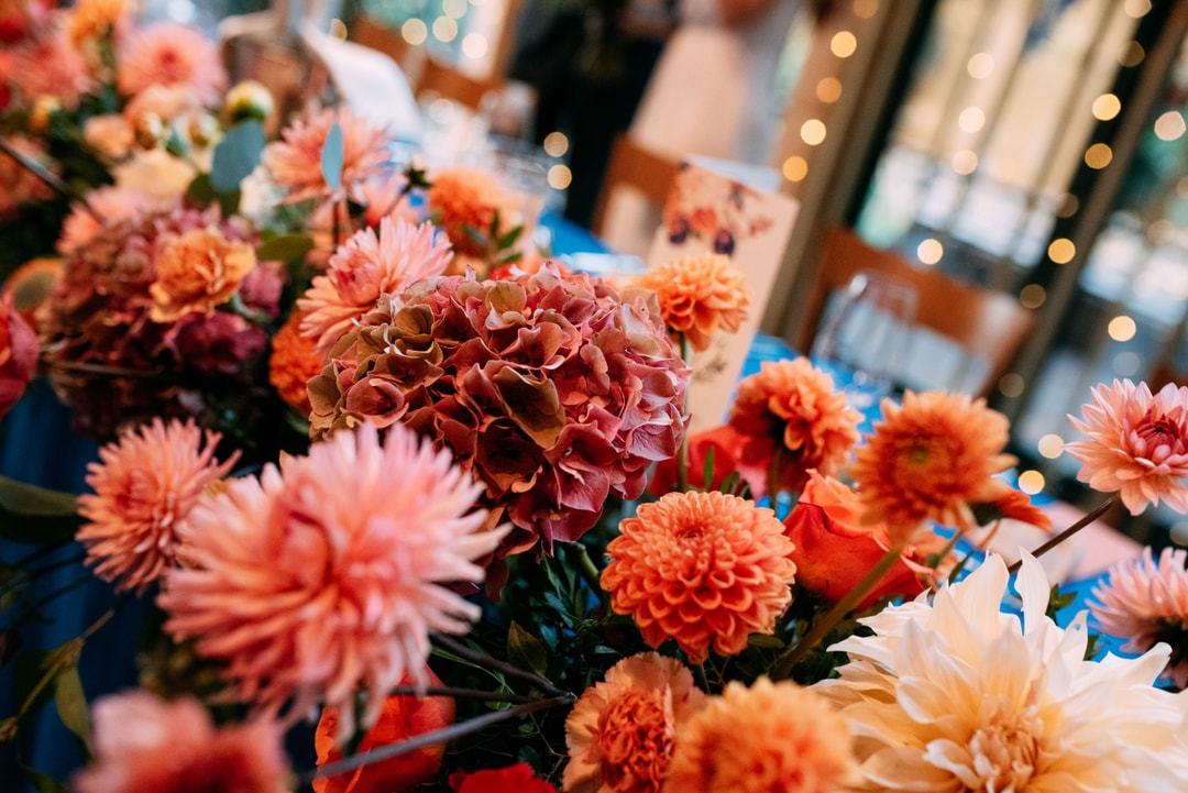 Zbliżenie na kompozycję kwiatową na stół z kwiatami w odcieniach łososiowym, różowym i pomarańczowym