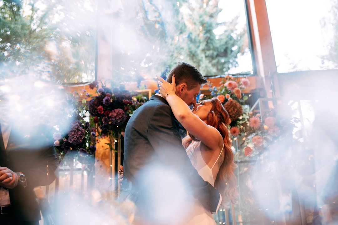 Para tańcząca przy łuku kwiatowym z różami i zielenią, światło słoneczne, bokeh w tle