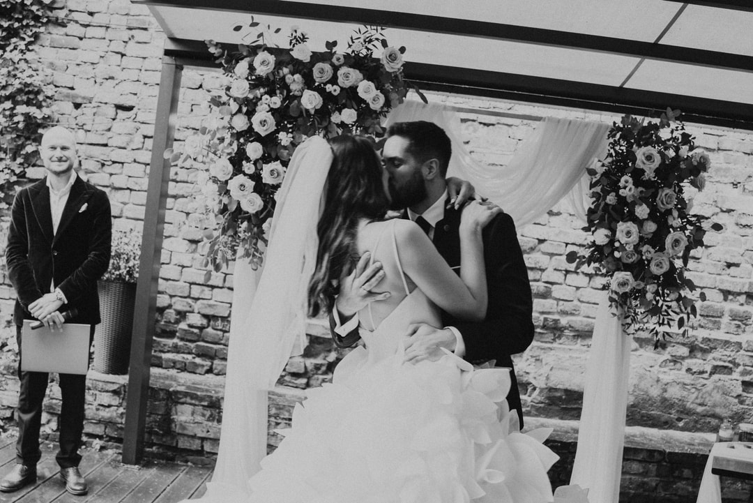 Czarno-biała scena pocałunku pary młodej podczas ceremonii ślubnej