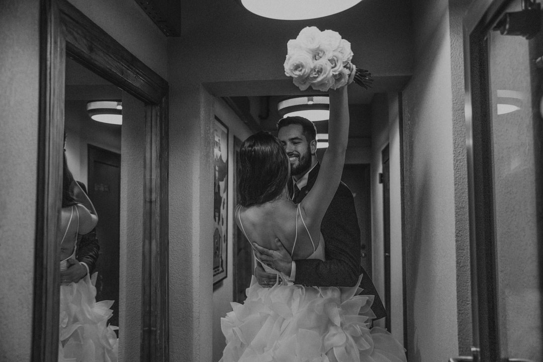 Czarno-biała fotografia pary młodej trzymającej bukiet w korytarzu