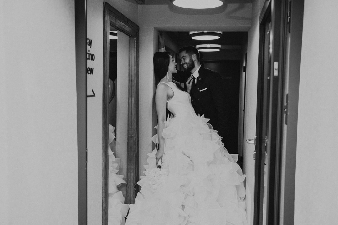 Para młoda przytulająca się w korytarzu, w eleganckiej białej sukni ślubnej