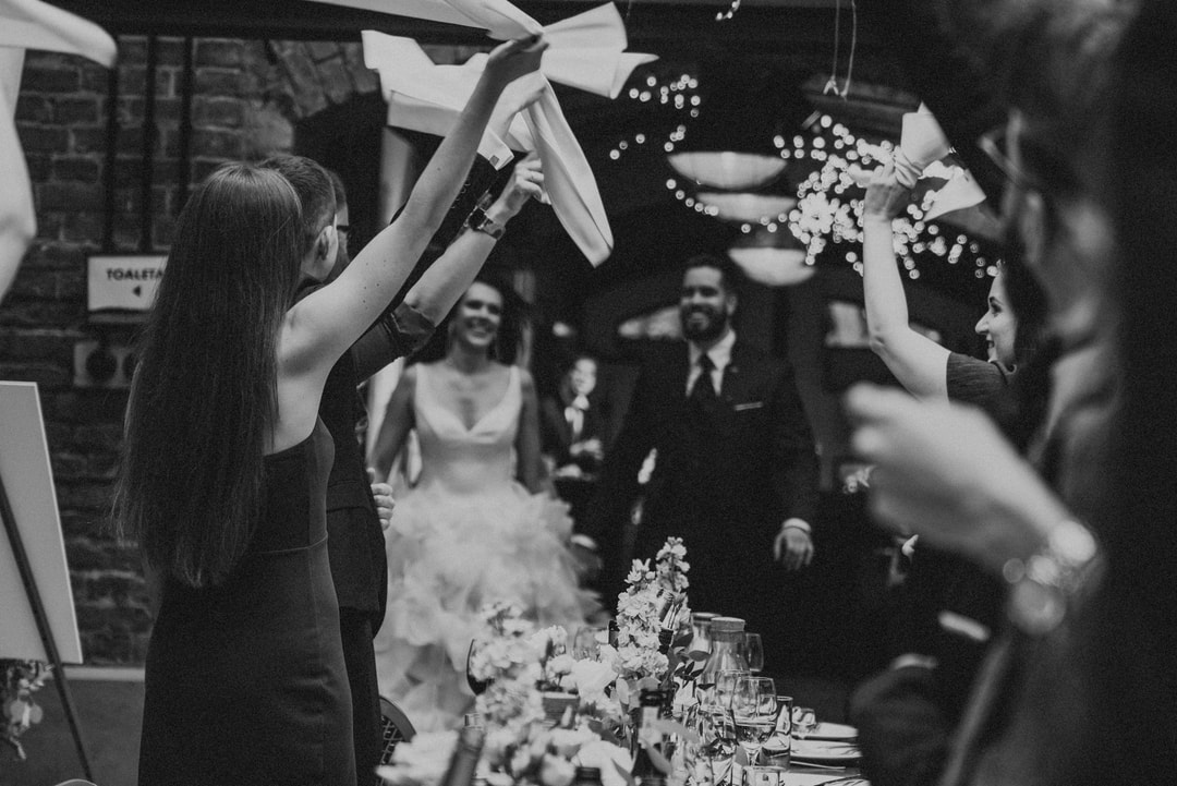 Goście weselni unoszący serwetki podczas przyjęcia w stylowym, ceglanym wnętrzu