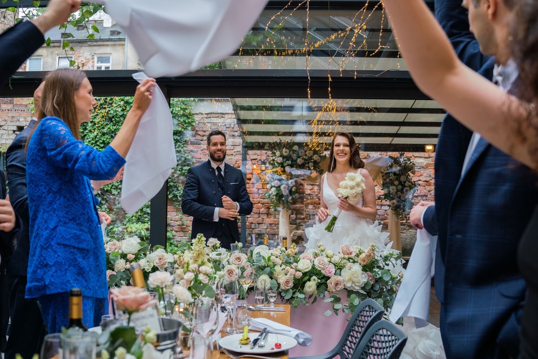 Dekoratorzy ślubni przygotowujący stół główny z białymi i pastelowymi kwiatami