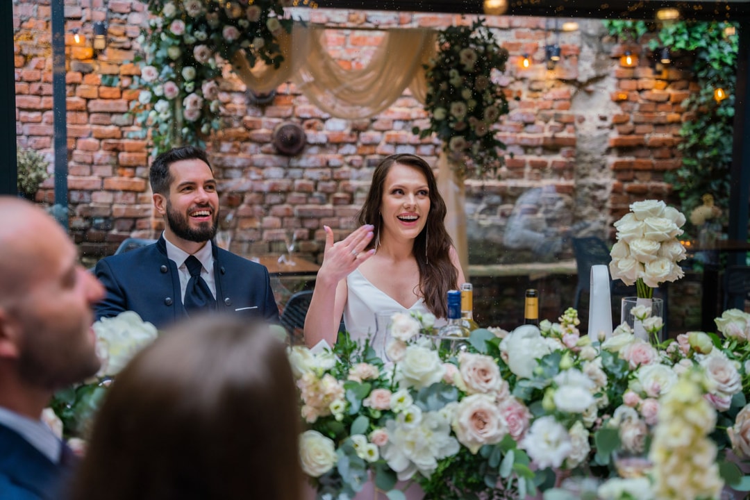 Para młoda śmiejąca się podczas przyjęcia, otoczona bukietami białych kwiatów