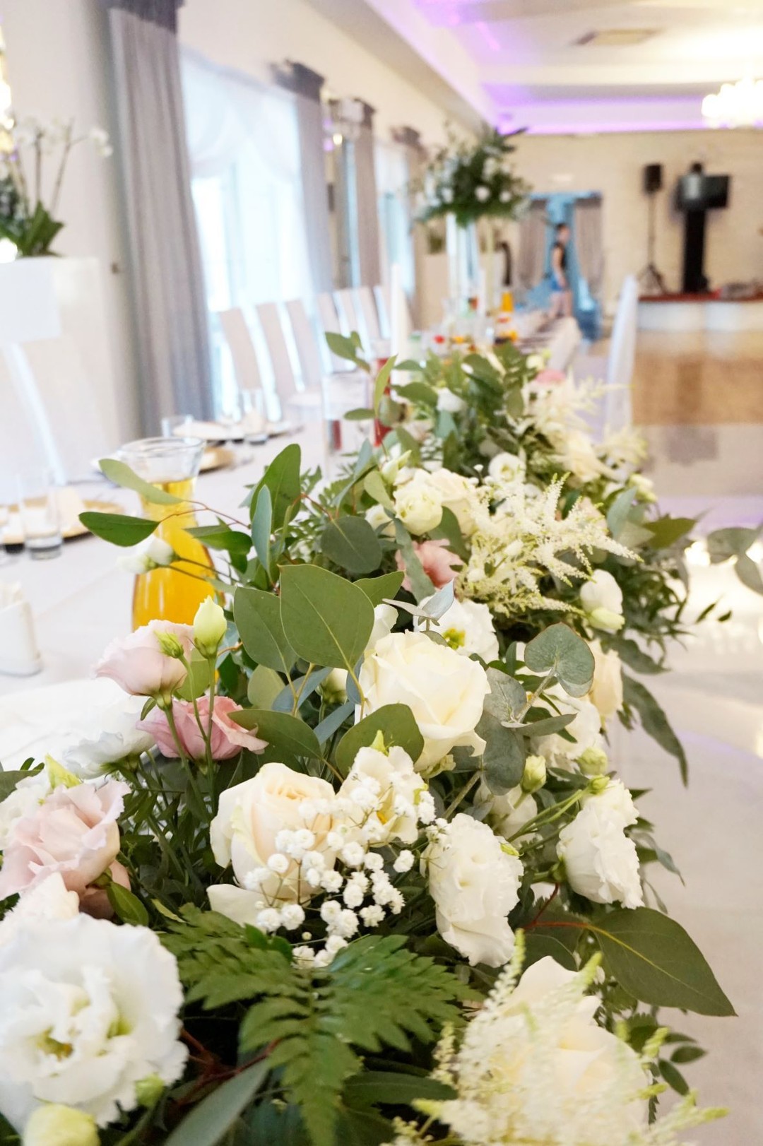 Frontowa dekoracja stołu prezydialnego pełna kwiatów i zieleni