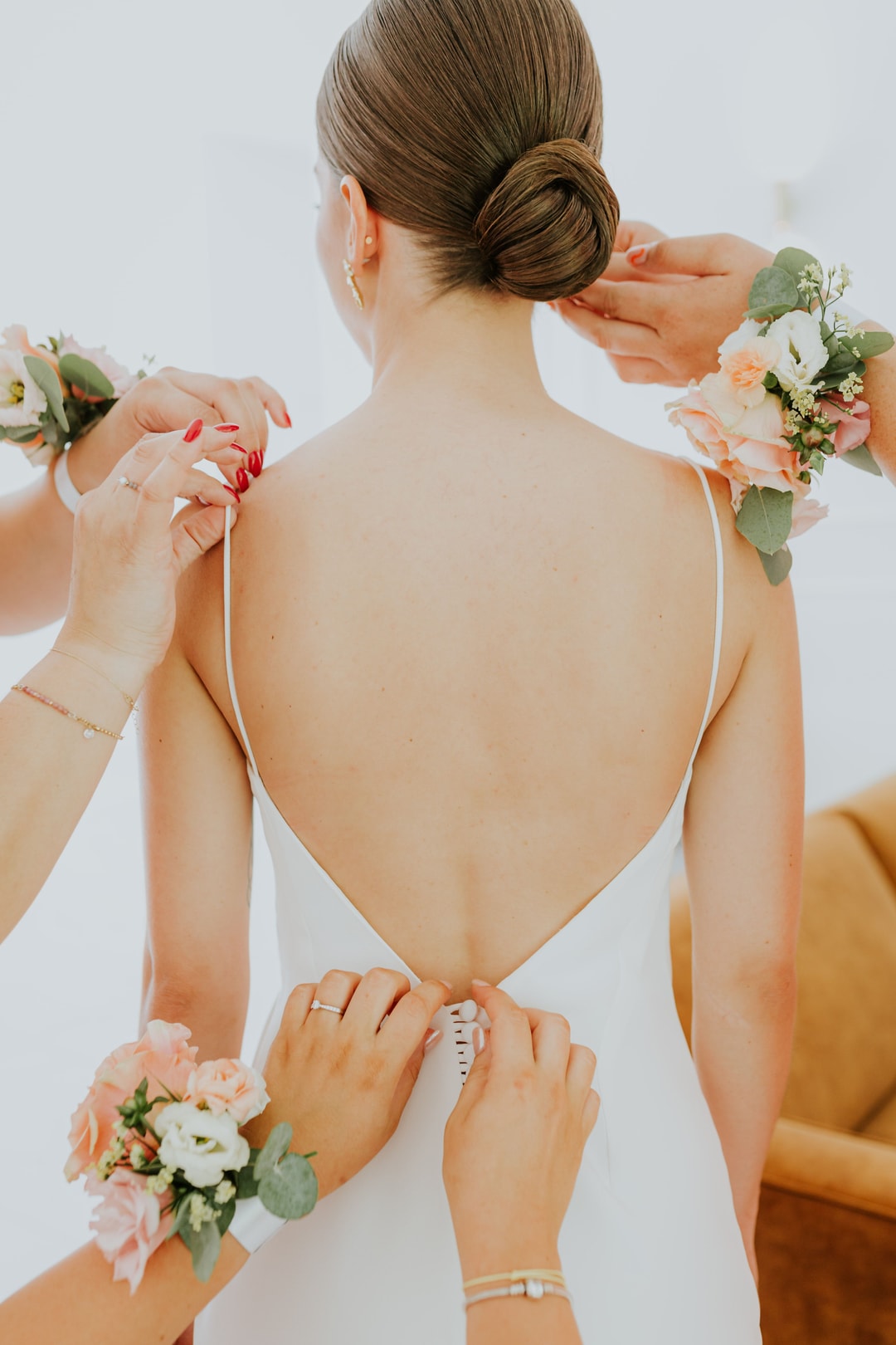 Panna młoda z rozpiętymi plecami, floryści przyczepiają korsarz i butonierki z jasnych kwiatów