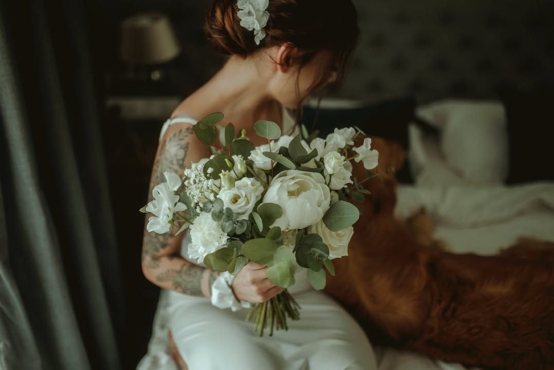 Kobieta trzymająca bukiet ślubny z białymi kwiatami, zielenią eukaliptusa i delikatnym wiankiem we włosach