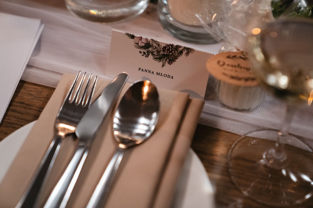 Zastawa stołowa z menu, srebrnym sztućcem i szklankach na białej tkaninie, dekoracja stołu