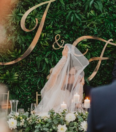 Zielona ścianka ślubna, złote inicjały i dekoracja stołu prezydialnego